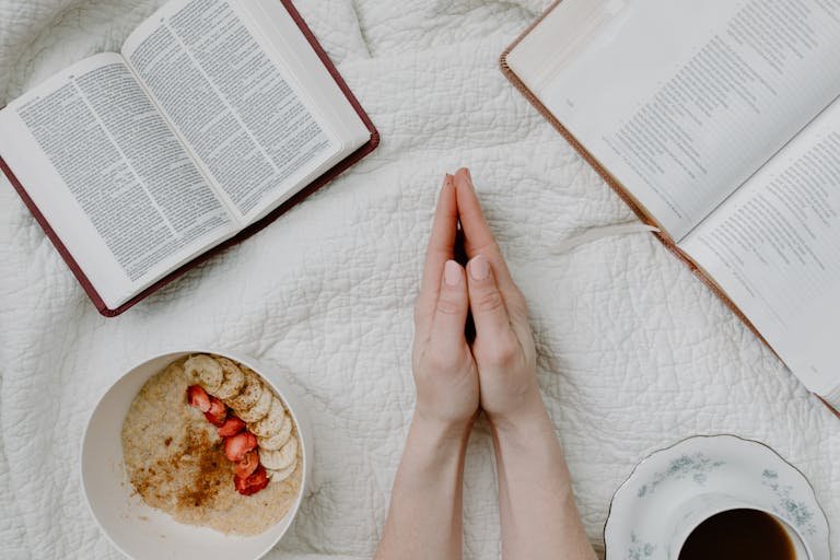 A serene morning scene with a person praying, an open Bible, oatmeal, and coffee.